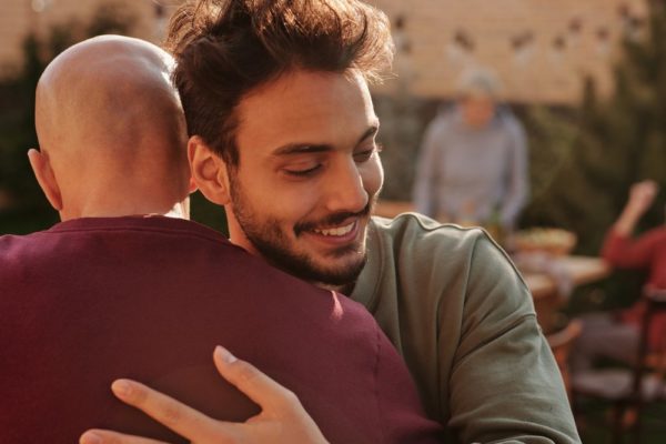 man in long sleeve shirt hugging a friend