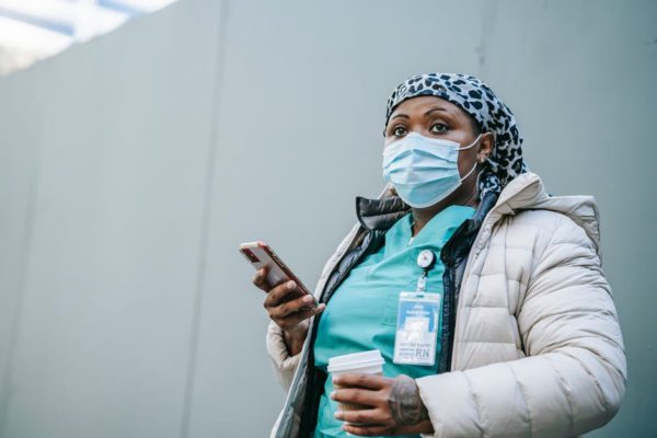 a First Responder looking tired is holding a coffee cup and a cellphone