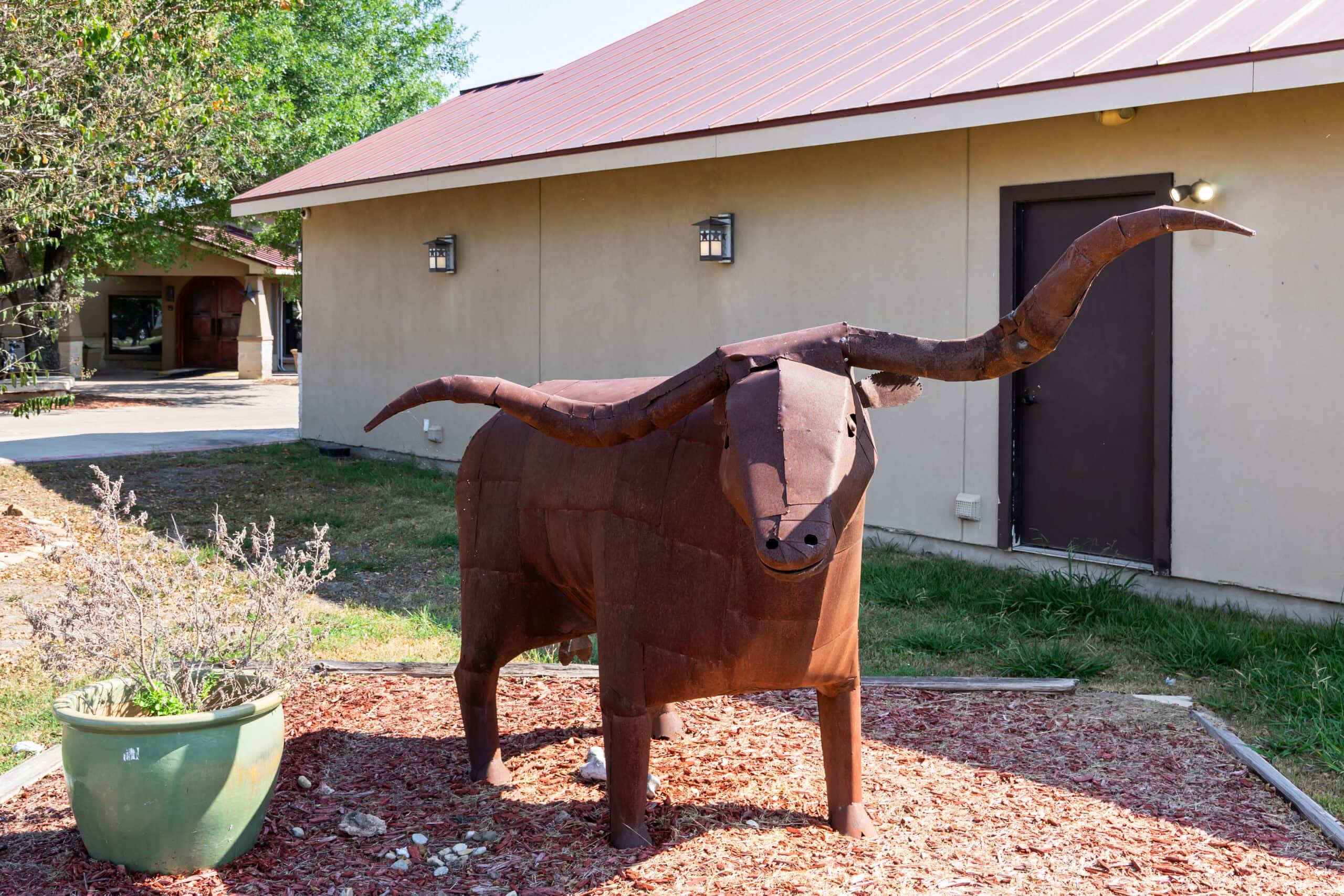 Metal longhorn sculpture outside a ranch building